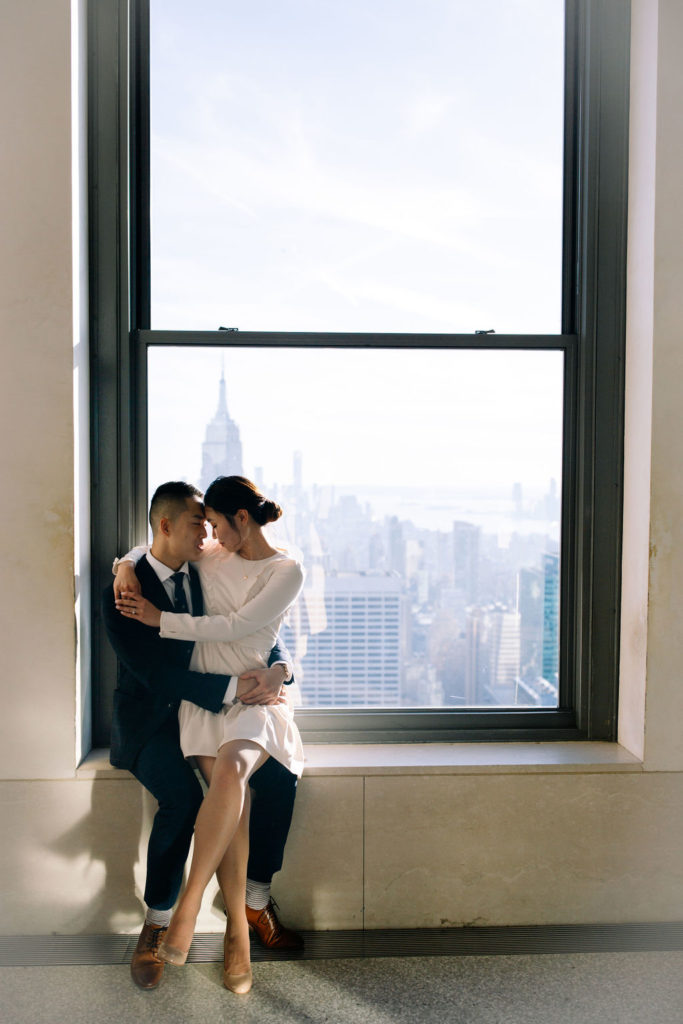 Couple hugging by the window at Top of the Rock 