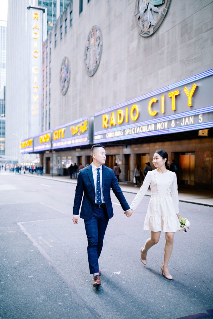 Couple holding hands walking down the streets of radio city